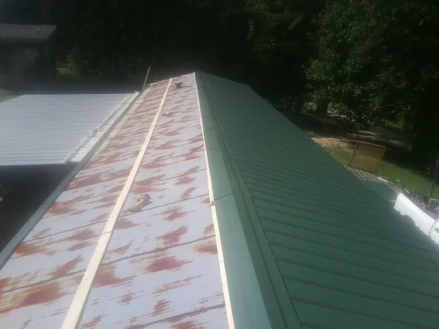 Old rusted panels beside newly installed green metal roofing — Wind Damage Roof Repair by Roofing Brothers in Tiverton
