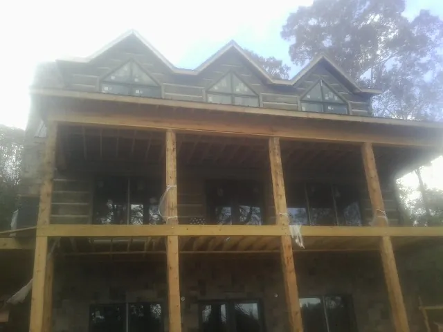 Dormers and porch framing on a large log home under construction — Roof Coating work by our crew in Tiverton