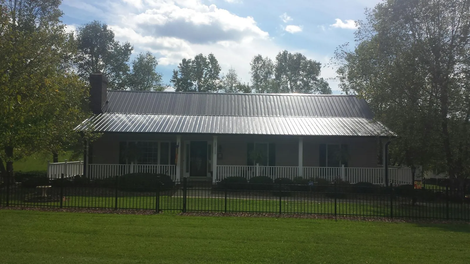 Gray metal roof on a brick ranch with a full width front porch — Gutter Guard Installation work by our crew in Tiverton