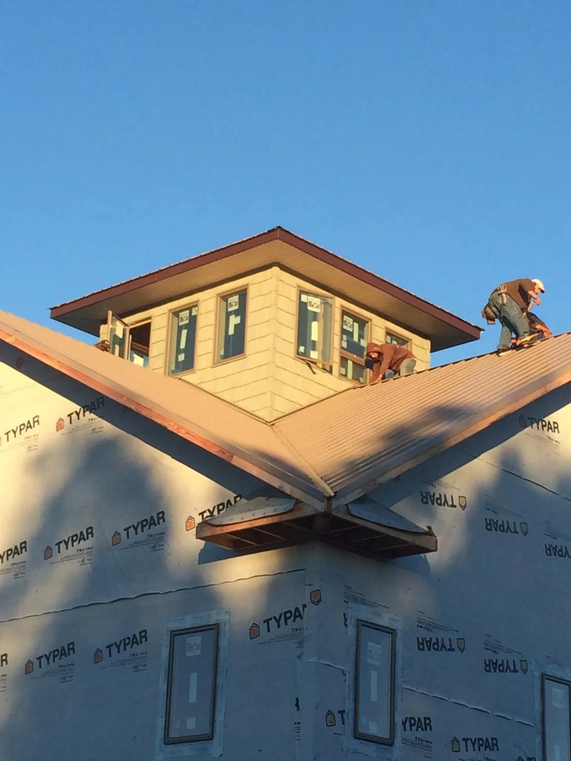 Roofers working around a rooftop cupola on a new metal roof at sunset — Roof Waterproofing in Tiverton by Roofing Brothers